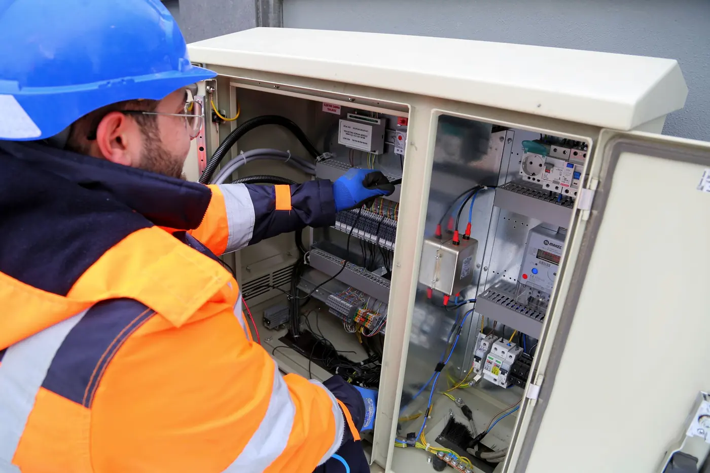 Eletricista com equipamento de proteção trabalhando em um painel