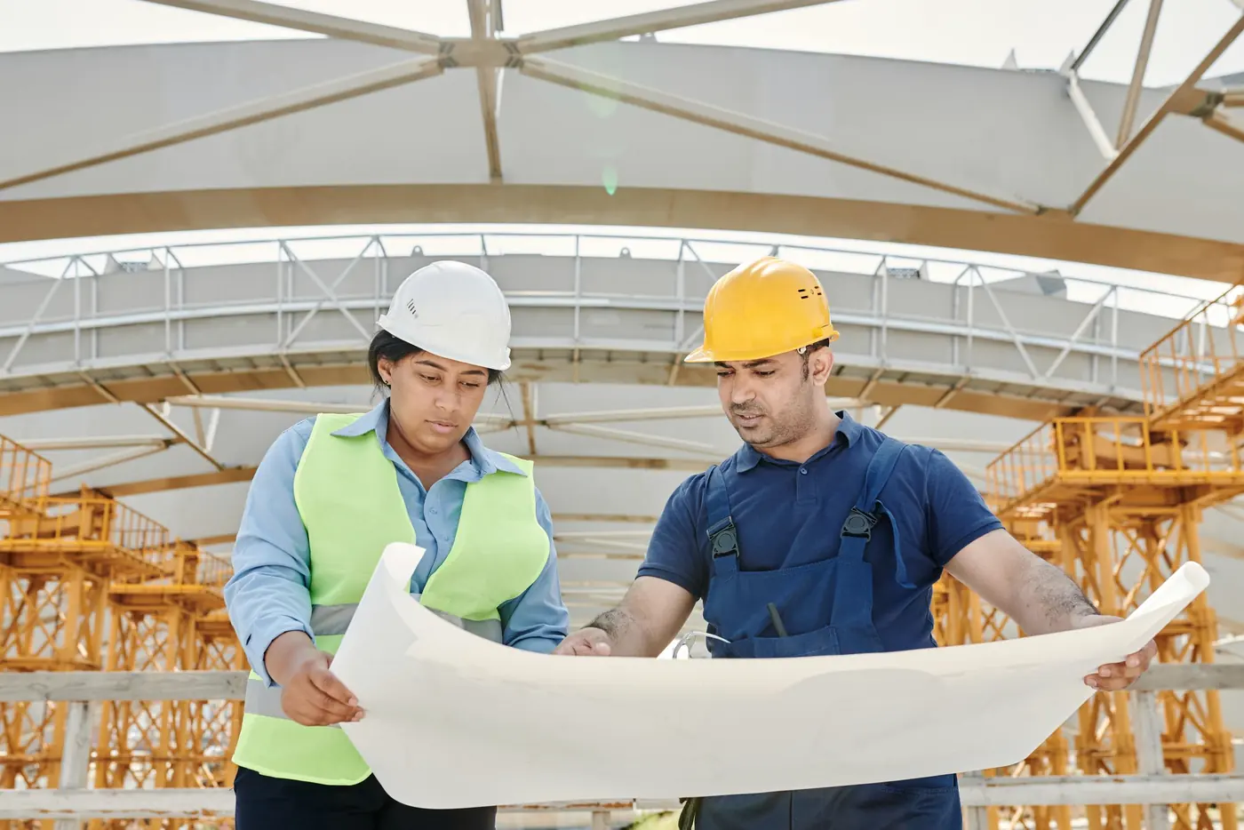 Engenheiros de capacete analisando o projeto na obra