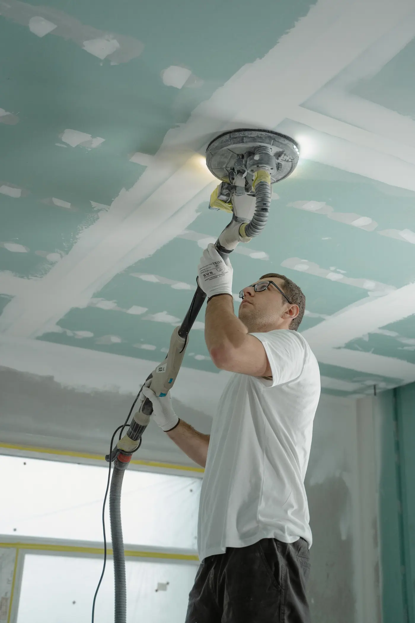 Profissional lixando o forro de gesso durante uma reforma