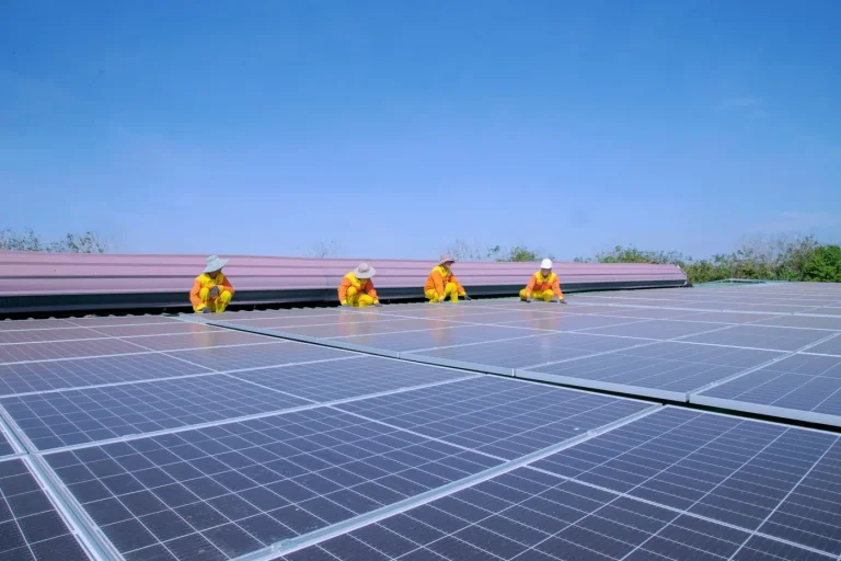 Equipe instalando placas solares sobre a cobertura de um galpão