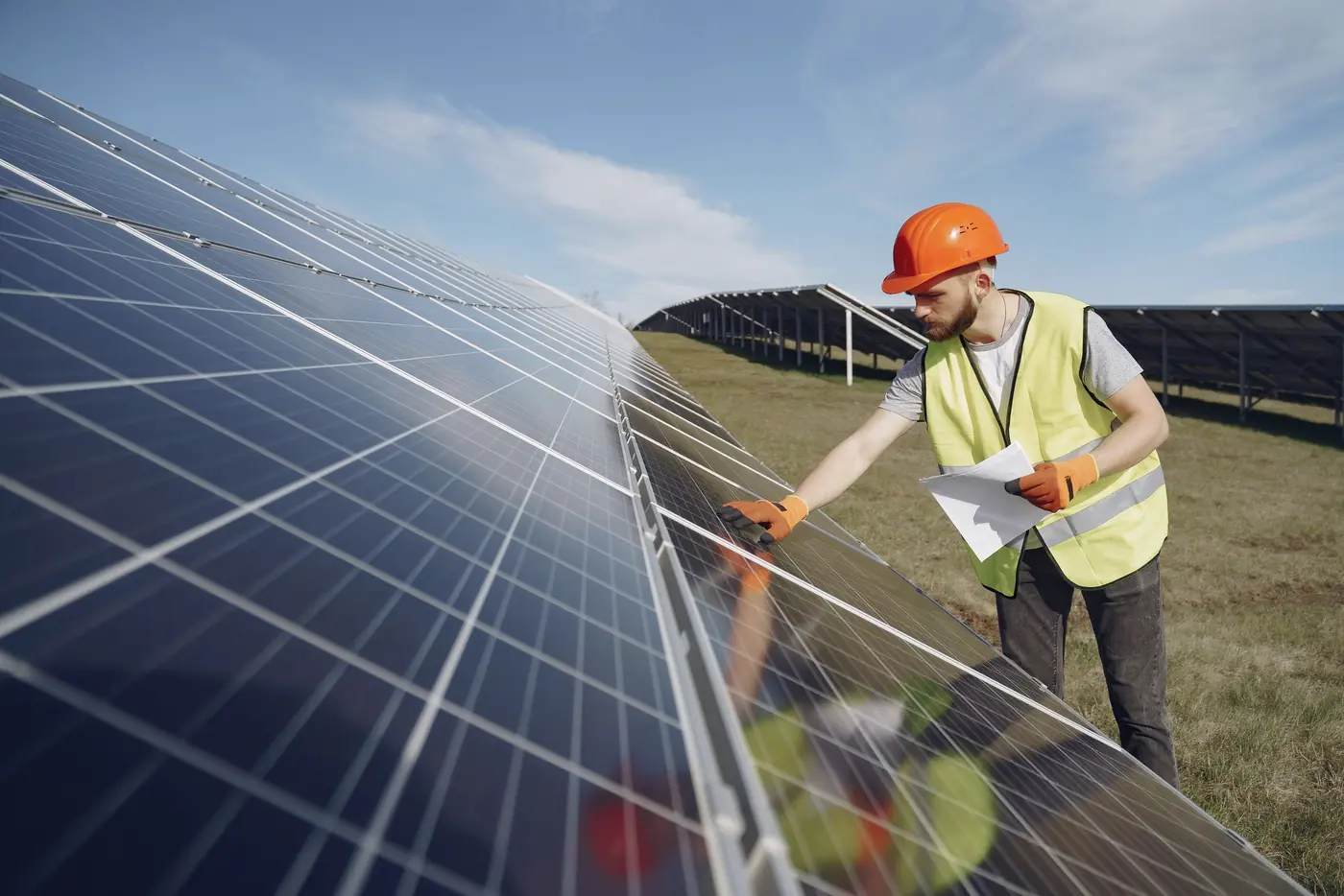 Técnico de capacete inspecionando placas solares em uma usina