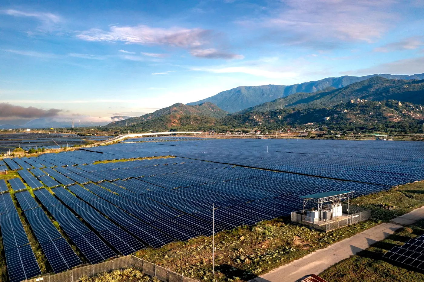 Usina solar em campo aberto, com montanhas ao fundo