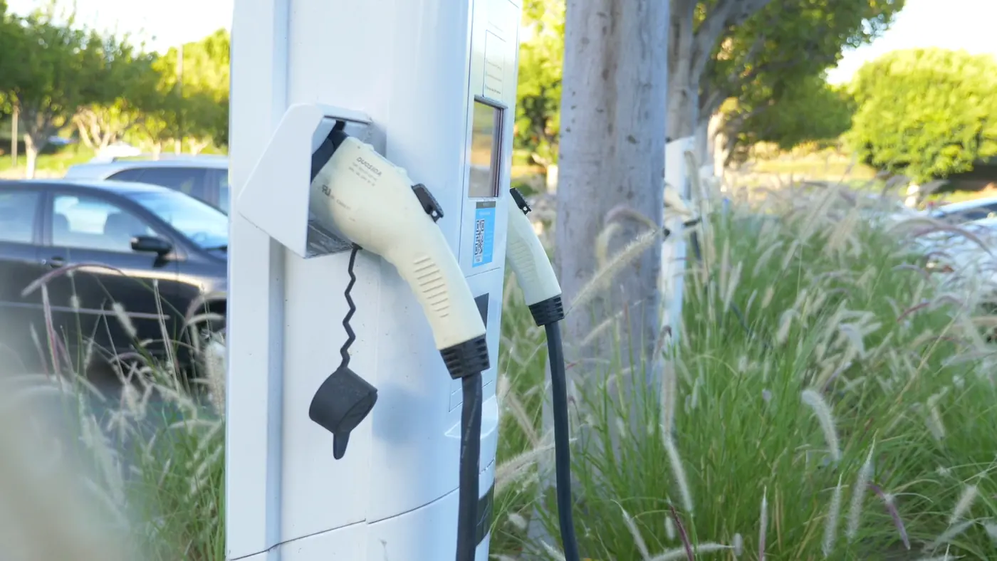 Carregador de veículos elétricos em estação de recarga, com carro ao fundo